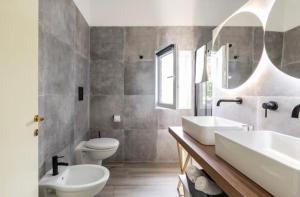 a bathroom with two sinks and a toilet at Aragon Cottage Apartments in Le Castella