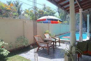 a patio with a table and chairs and an umbrella at Mango Tree House in Beruwala