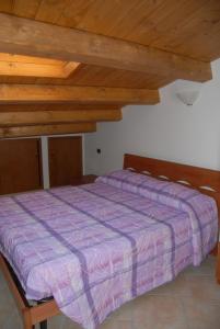 a bedroom with a purple bed with wooden ceilings at Agriturismo Miralago in Scanno