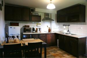 a kitchen with dark wooden cabinets and a table with chairs at Smolniki 28 in Smolniki