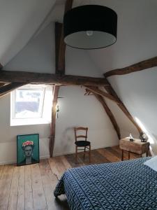 ein Schlafzimmer mit einem Bett, einem Fenster und einem Stuhl in der Unterkunft Gîte des Lilas 