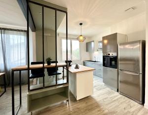 a kitchen with a stainless steel refrigerator and a counter at Design Moderne Spacieux - Hyper Centre - Parking in Mont-de-Marsan