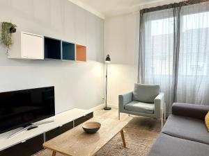 ein Wohnzimmer mit einem TV, einem Sofa und einem Stuhl in der Unterkunft DESIGN MODERNE SPACIEUX - Familial in Mont-de-Marsan
