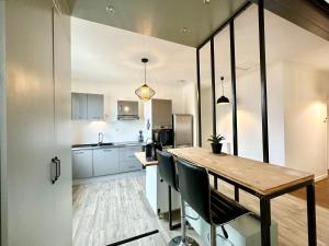 a kitchen with a wooden table and chairs at Design Moderne Spacieux - Hyper Centre - Parking in Mont-de-Marsan +17 photos