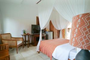 um quarto com uma cama de dossel, uma secretária e uma televisão em Gayatri em Ubud