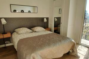a bedroom with a bed and a mirror on the wall at Top floor nest, balcony close to sea and old-town in Nice