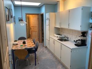 cocina con armarios blancos, mesa y sillas en Vibereden en Vorbasse