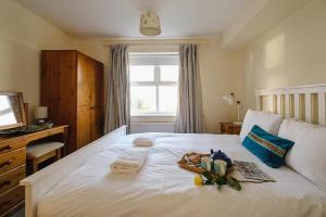 a bedroom with a white bed with towels and a window at 1 Coastguard Court in Aldeburgh