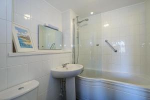 a white bathroom with a sink and a shower at 1 Coastguard Court in Aldeburgh