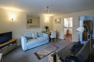 a living room with a blue couch and a television at 1 Coastguard Court in Aldeburgh