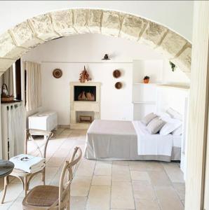 a white bedroom with a bed and a table and chairs at Masseria Vittoria in Acaya