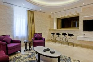a living room with purple chairs and a tv at The Proud Hotel Al Khobar in Al Khobar