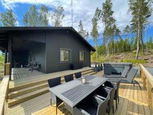 eine Holzterrasse mit einem Tisch und einem Grill in der Unterkunft Villa Lyxfällan in Kimitoön