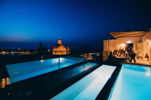 a pool on the roof of a building at night at The Embassy Valletta Hotel in Valletta