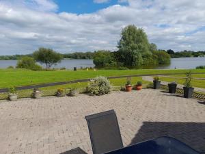 a patio with a view of a park and a body of water at THE LAKE HOUSE: a delightful and peaceful retreat. in Derrymacash