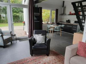 uma sala de estar com um sofá, uma cadeira e uma mesa em Vrijstaande recreatievilla met ruime omheinde tuin em Posterholt