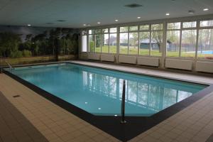 a large swimming pool in a large building at Vrijstaande recreatievilla met ruime omheinde tuin in Posterholt