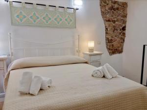 een slaapkamer met een bed met handdoeken erop bij Sardinian Gallery Fonte in Bosa