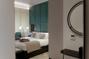a bedroom with a large bed with a green headboard at The Embassy Valletta Hotel in Valletta