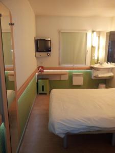 a hospital room with a bed and a tv at ibis Budget Gennevilliers Asnieres in Gennevilliers