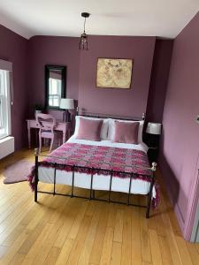 a bedroom with a bed with a purple wall at Efail Y Garn in Swansea