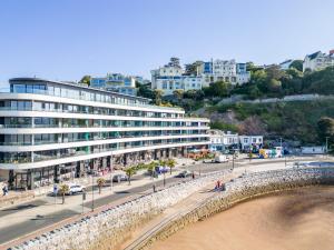 a large building next to a beach with cars at Kethla House in Torquay