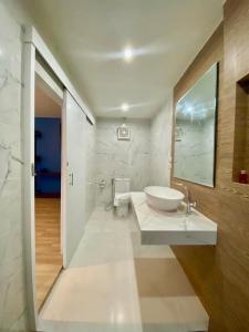 Baño blanco con lavabo y espejo en Blue Ba You Resort, en Ban Khlong Haeng