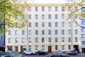 ein weißes Gebäude mit davor geparkten Autos in der Unterkunft Orchid&Sakura studios Kamppi in Helsinki