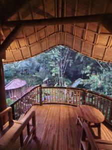 una terraza de madera con mesa y bancos. en Pondok Salacca#bamboohouse#, en Candidasa