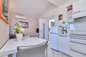 a kitchen with white appliances and a white table and chairs at Appartment Ksenija 1 in Mali Lošinj