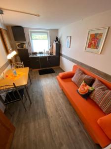 un soggiorno con divano arancione e tavolo di Ferienwohnung Witzig Inh Rita Weitmann a Ingelheim am Rhein