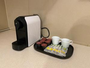 a tray with cupcakes and coffee cups next to a computer at Klimatyczny apartament Romek 5 minut od Krupówek in Zakopane