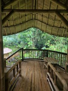 una terraza de madera con un banco y una mesa en Pondok Salacca#bamboohouse#, en Candidasa