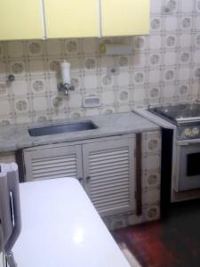 a kitchen with a sink and a stove at Apartamento Cote d'Azur Enseada in Guarujá