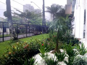 a garden with plants in front of a fence at Apartamento Cote d'Azur Enseada in Guarujá