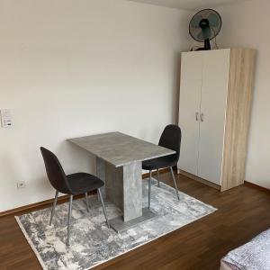 a dining room table with two chairs and a cabinet at 1 Zimmer Apartment DG in Eislingen