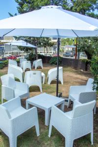 un groupe de chaises et de tables blanches sous un parasol dans l'établissement Hotel Terrazas by CPH, à Villa Carlos Paz