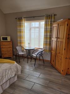 um quarto com uma mesa e cadeiras e uma janela em Daisy cottage em Robertson