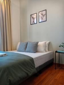 uma cama num quarto com duas fotografias na parede em Staycationbyrieymona - 3BR Condo, CLIO 2, Putrajaya em Putrajaya