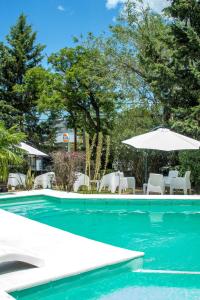 una piscina con sombrilla, sillas y sillas en Hotel Terrazas by CPH en Villa Carlos Paz