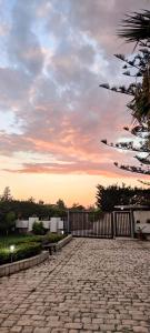 a brick road with a fence in front of a sunset at Green Rooms - Casa nel verde in Pachino