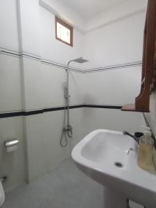 a white bathroom with a sink and a shower at adam's apple homestay in Ella