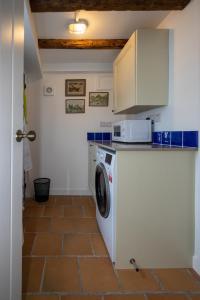 a kitchen with a washing machine and a microwave at The Wave - 3 bed beach front home in Sheringham in Sheringham