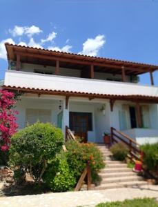 a house with stairs and flowers in front of it at XHEKO ROOMS in Dhërmi