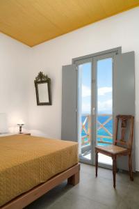 a bedroom with a bed and a chair and a window at MIKRES CYCLADES DONOUSSA in Donoussa