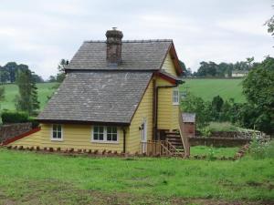 a yellow house with a roof on top of a field at The Signal Box (Cliburn) in Penrith