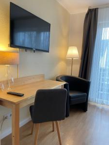 um quarto com uma secretária, uma televisão e uma cadeira em Apartmenthaus Sonnen em Dusseldorf