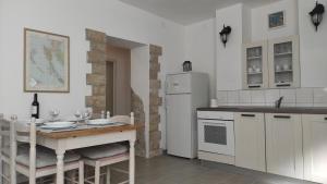 a kitchen with a table and a white refrigerator at Apartment Loparina in Nerezine