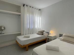 a white room with two beds and a window at Apartamentos Mar a mar in Cala en Forcat +13 photos