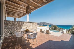 a patio with a table and chairs and the ocean at Onar Beach Houses in Amoopi
